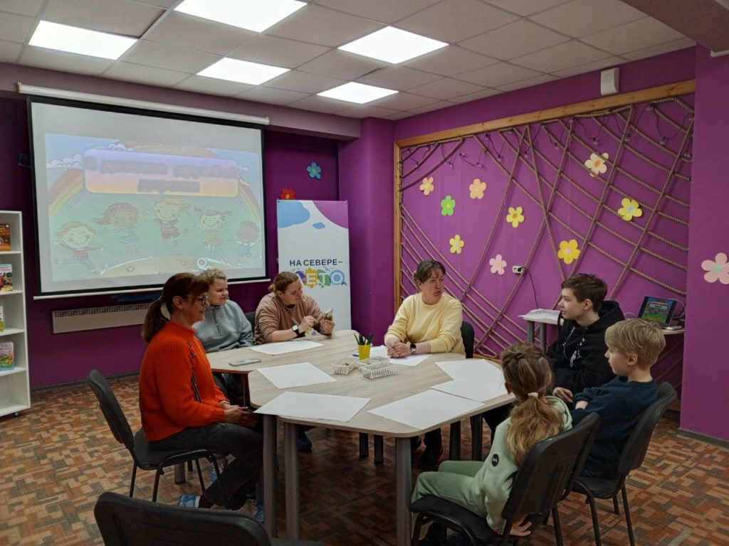 четверо детей и двое взрослых слушают рассказ библиотекаря