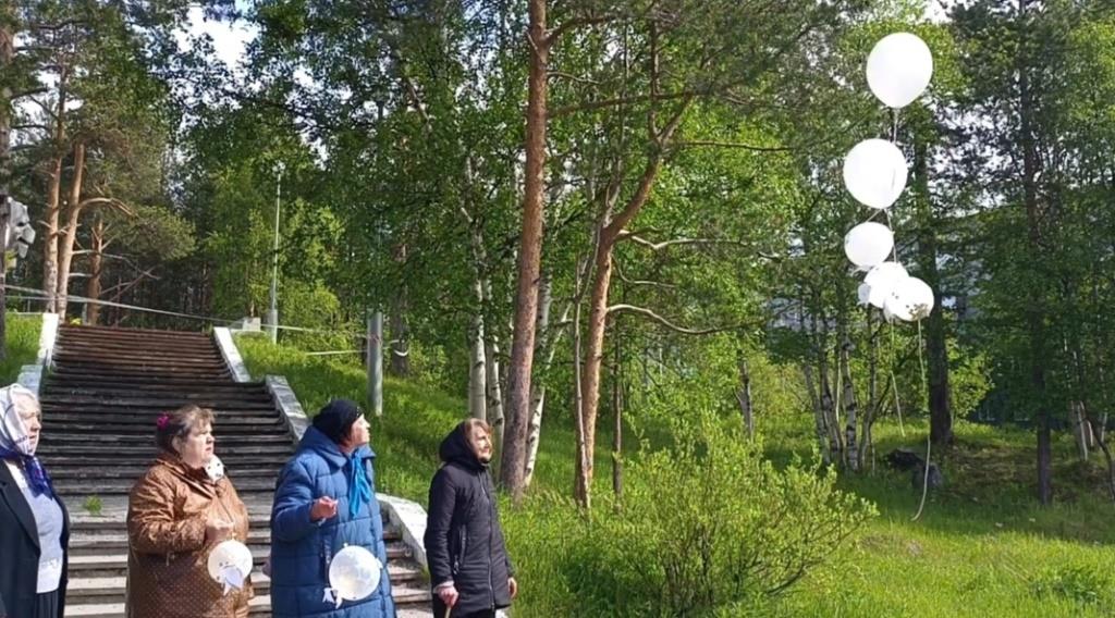 Пожилые люди 4 человека запустили в небо белые воздушные шары с голубями.