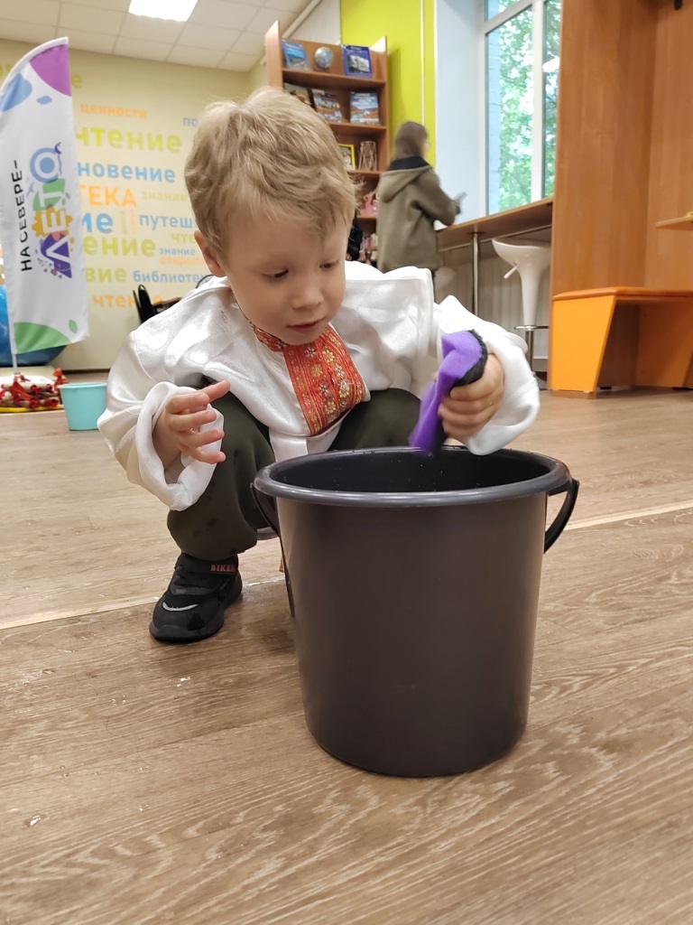 Воспитанник играет с водой из ведра