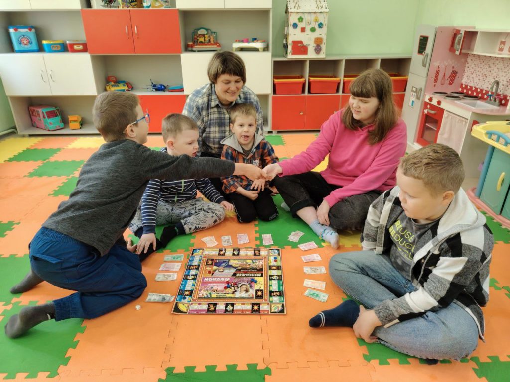 4 мальчика, одна девочка и специалист, один из игроков (мальчик) передает девочке игровую карточку
