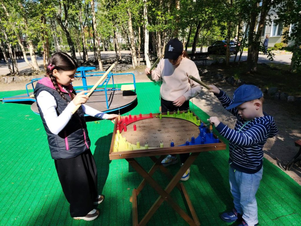 две девочки и мальчик увлеченно играют в настольно-спортивную игру